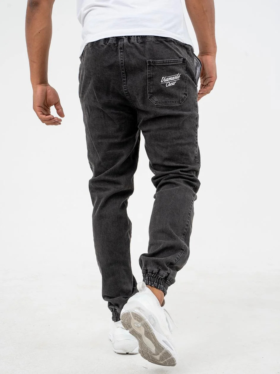 Mężczyzna w czarnych joggerach jeansowych z firmy Diamante Wear, gruby materiał z przetarciami black washed i mocnym ściągaczem